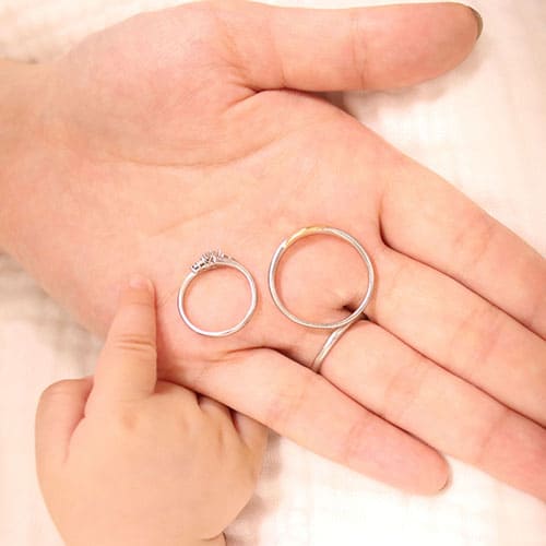 赤ちゃんとお母さんの手の上にペアリングが乗っているイメージ